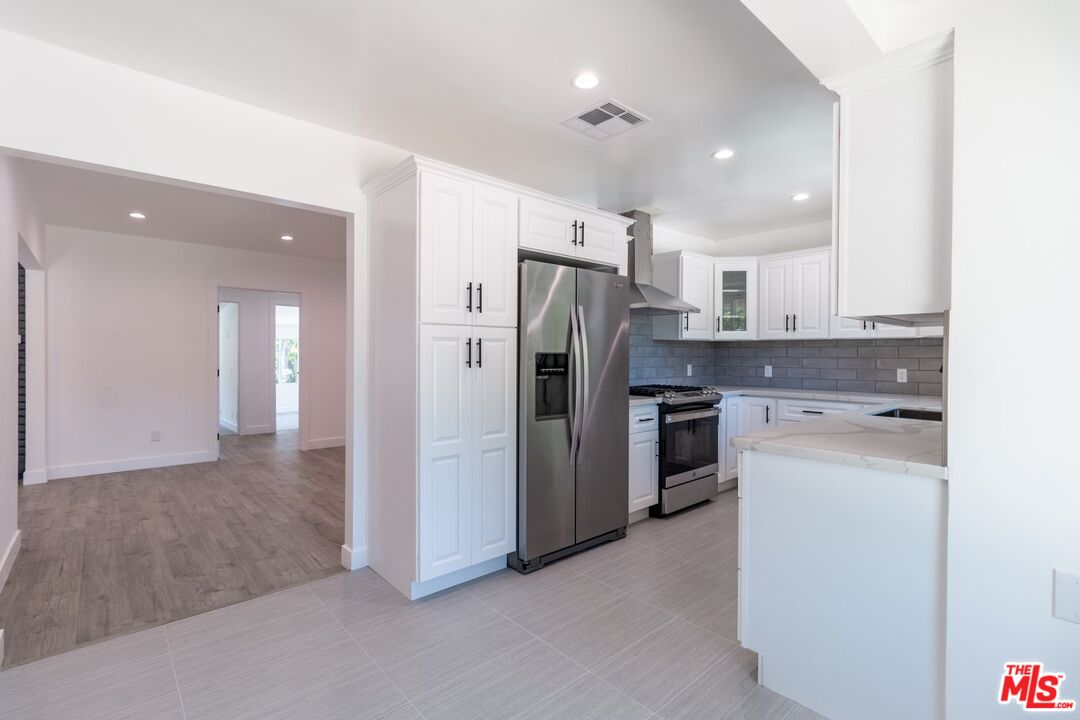 9416 Ruffner Avenue Northridge, CA 91343 - Photo 22 of 27 a kitchen with stainless steel appliances a refrigerator sink and cabinets