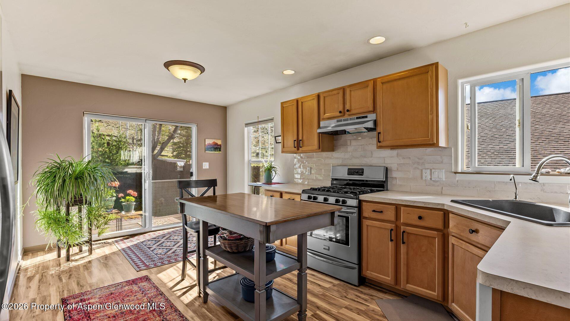 606 Lariat Loop New Castle, CO 81647 - Photo 8 of 27 a kitchen with stainless steel appliances granite countertop a stove top oven a sink dishwasher a dining table and chairs with wooden floor