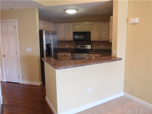 1133 Torrence Circle, Unit 1133 Davidson, NC 28036 - Photo 8 of 11 a kitchen with stainless steel appliances granite countertop a refrigerator a stove a sink and a microwave