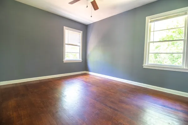 an empty room with wooden floor and windows