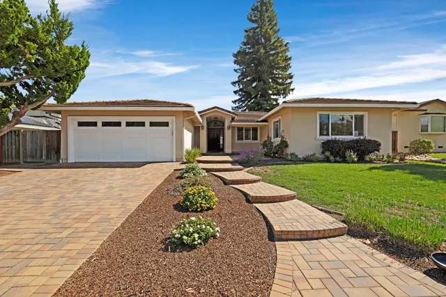 a front view of a house with a garden and trees