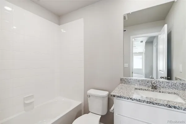 a bathroom with a granite countertop sink a toilet and shower