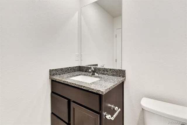 a bathroom with a granite countertop sink and a toilet