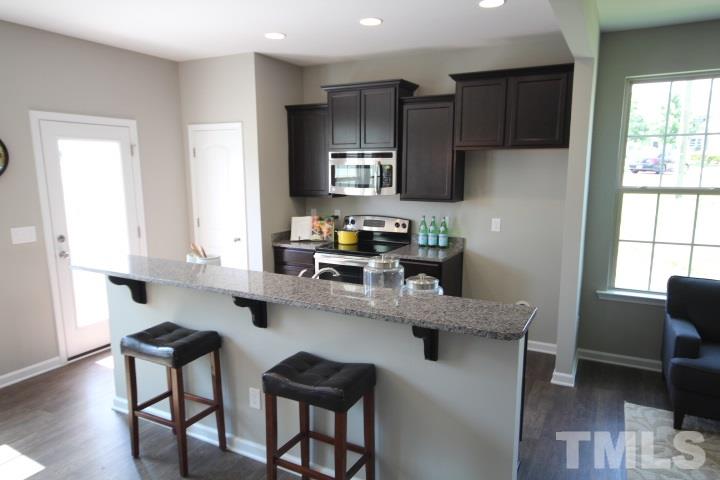 1014 Grand Ridge Drive Rolesville, NC 27571 - Photo 12 of 25 a kitchen with stainless steel appliances granite countertop a table chairs refrigerator and sink
