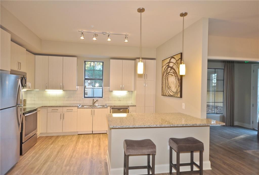 4011 Roswell Road, Unit 2311 Atlanta, GA 30342 - Photo 7 of 39 a kitchen with stainless steel appliances granite countertop a refrigerator a sink dishwasher a stove and white countertops with wooden floor