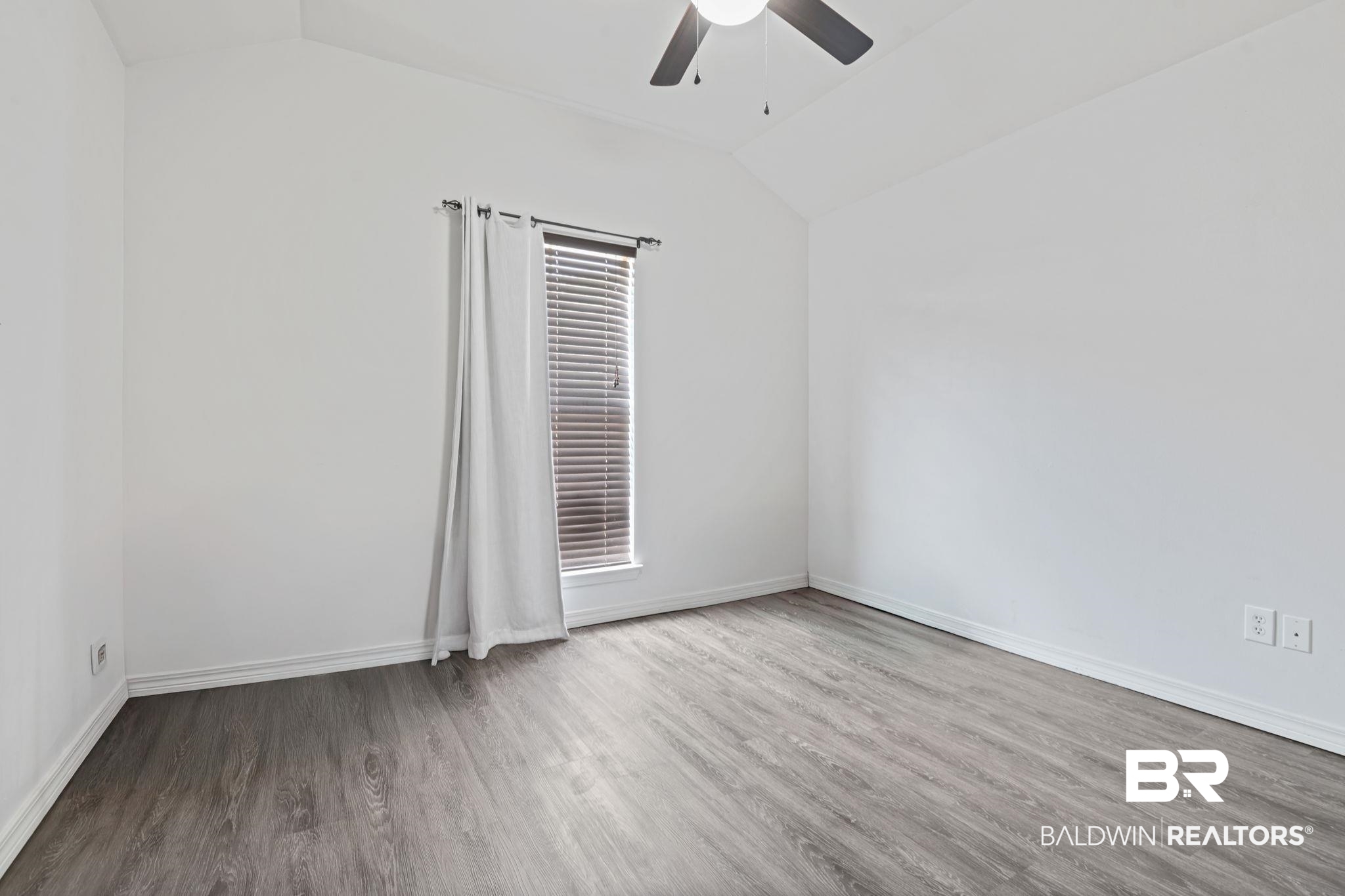 8956 Spring Grove North Mobile, AL 36695 - Photo 13 of 19 Unfurnished room featuring lofted ceiling, wood finished floors, a ceiling fan, and baseboards