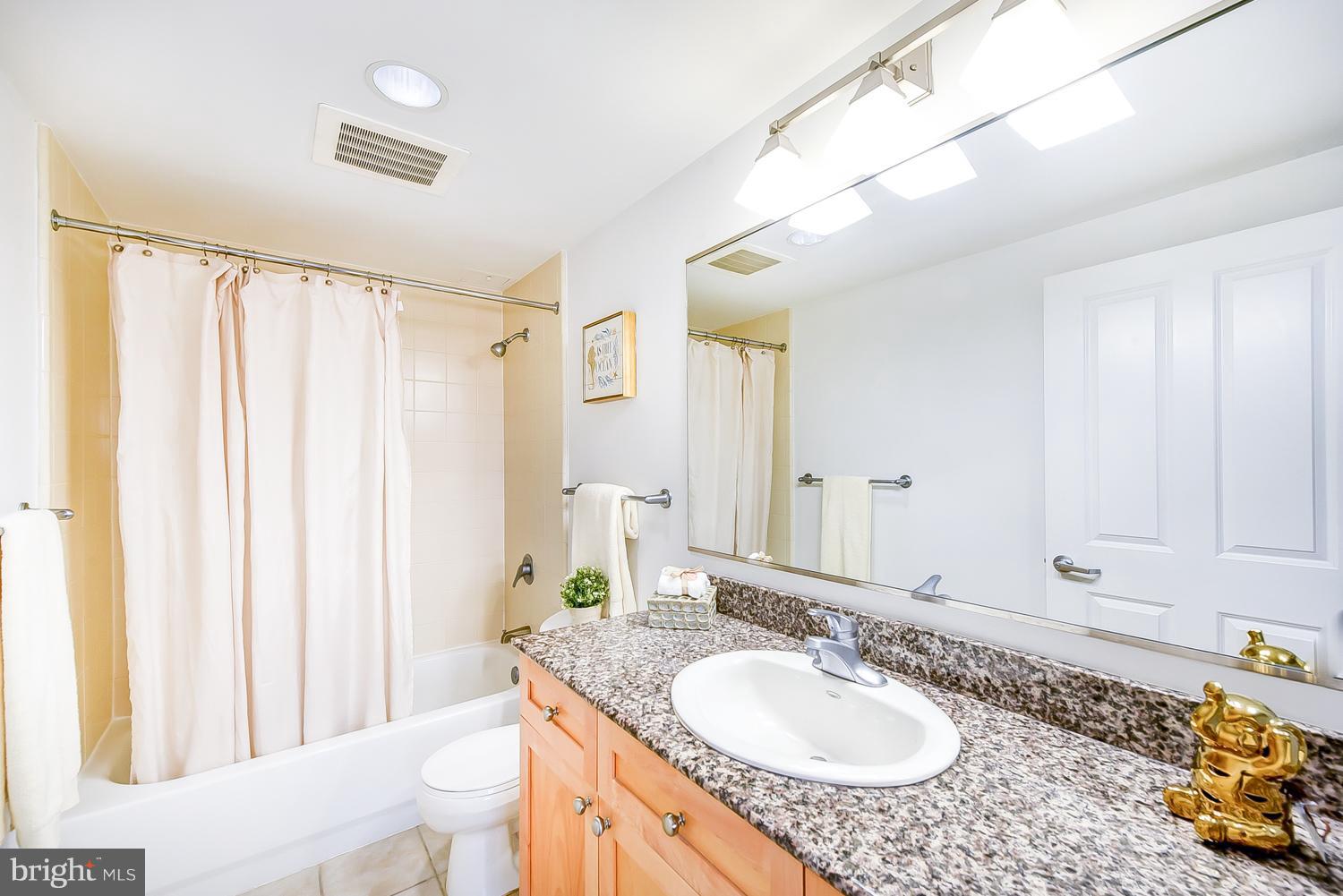 777 7th Street Northwest, Unit 924 Washington, DC 20001 - Photo 18 of 25 a bathroom with a granite countertop sink and a mirror a bathtub