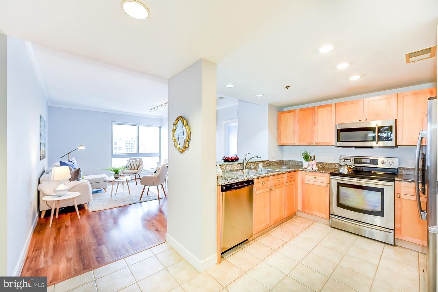 777 7th Street Northwest, Unit 924 Washington, DC 20001 - Photo 3 of 25 a kitchen with stainless steel appliances granite countertop a stove top oven a sink a dining table and chairs with wooden floor
