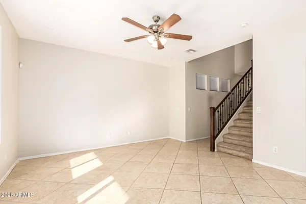 a view of an empty room with wooden floor and a ceiling fan