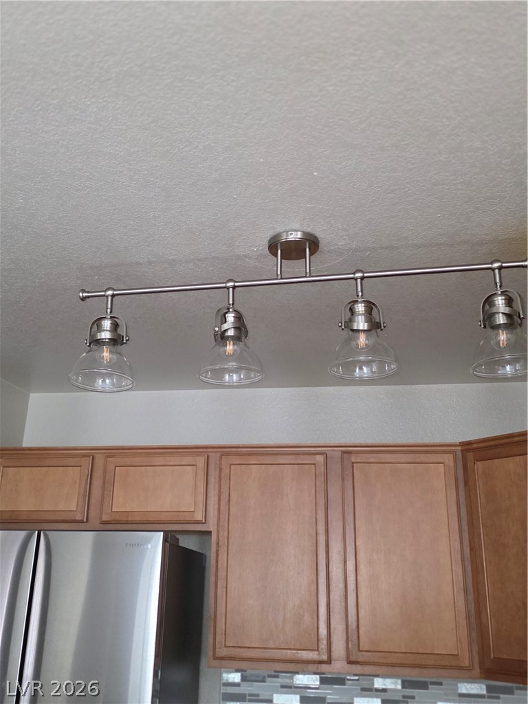 9325 West Desert Inn Road, Unit 239 Las Vegas, NV 89117 - Photo 11 of 29 Kitchen view of fridge, decorative light fixtures, wood finish cabinetry, and a textured ceiling