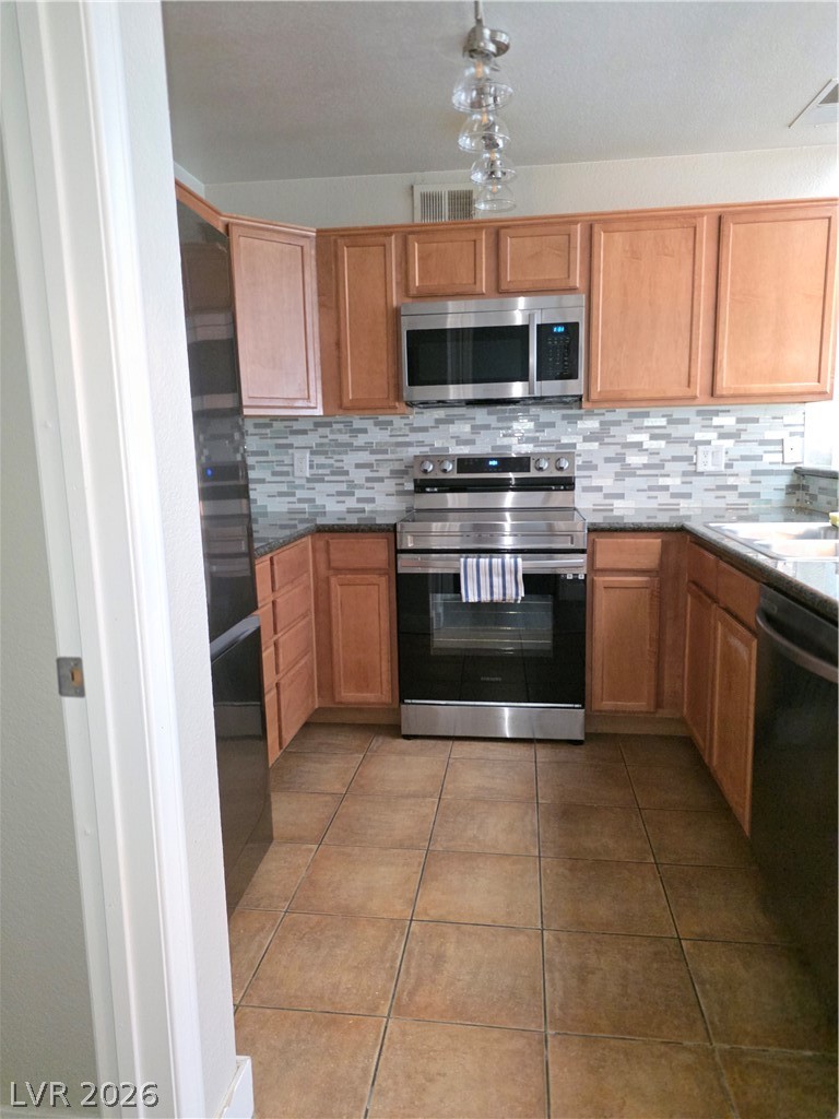 9325 West Desert Inn Road, Unit 239 Las Vegas, NV 89117 - Photo 12 of 29 Kitchen featuring stainless steel appliances, light tile patterned floors, tasteful backsplash, and dark stone counters