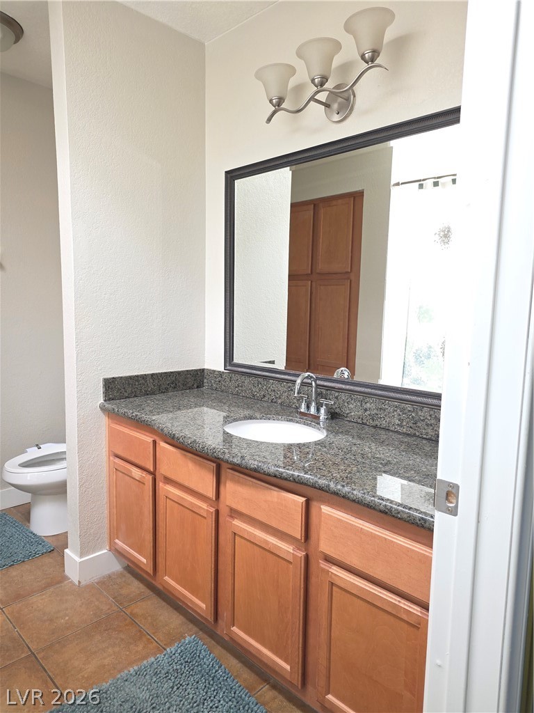 9325 West Desert Inn Road, Unit 239 Las Vegas, NV 89117 - Photo 19 of 29 Bathroom featuring vanity, a textured wall, and dark tile patterned flooring