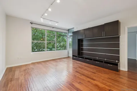 a view of an empty room with wooden floor and a window