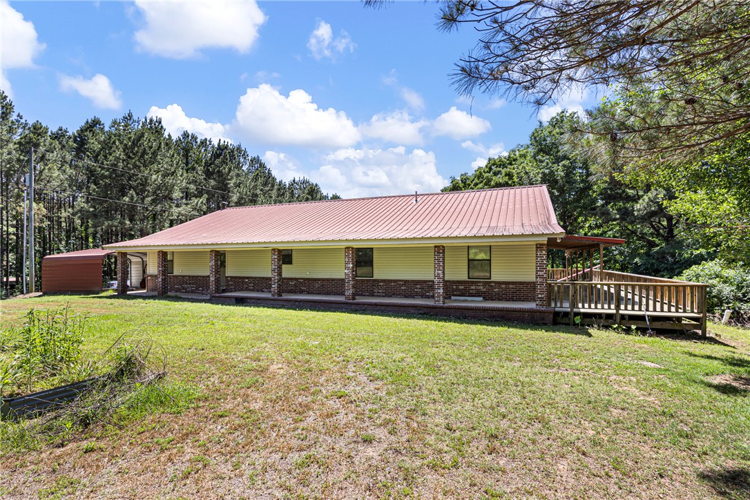 655 Charton Road Morrilton, AR 72110 - Photo 4 of 49 Ranch-style exterior featuring a red metal roof, covered front porch with brick column accents, and a wooden side deck