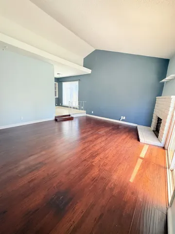 a view of empty room with wooden floor and window