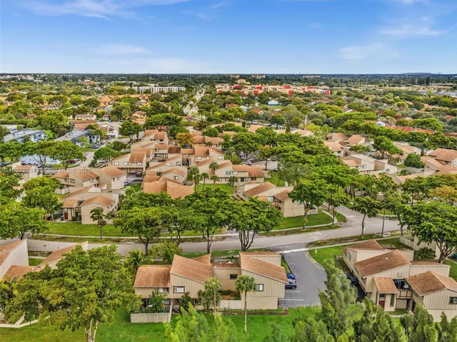 an aerial view of residential houses with outdoor space and trees