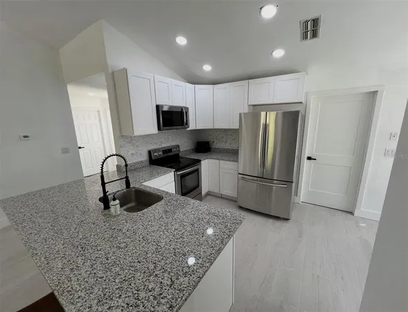 a kitchen with stainless steel appliances granite countertop a refrigerator stove top oven a sink and dishwasher