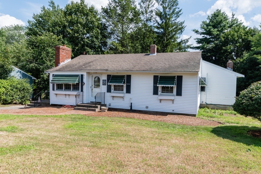 a front view of a house with a garden and trees