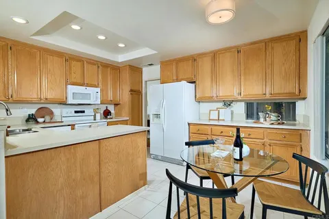 a kitchen with stainless steel appliances granite countertop a refrigerator a stove a sink dishwasher and white cabinets with wooden chairs
