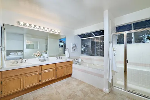a spacious bathroom with a double vanity sink a mirror and a bathtub