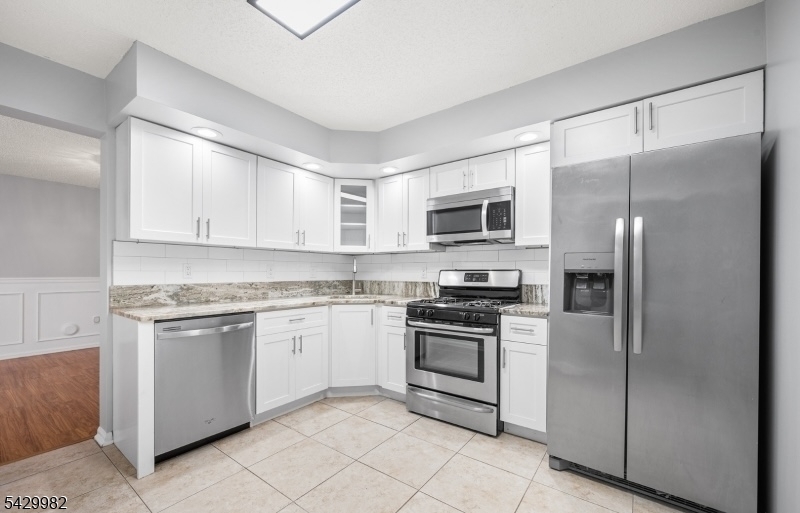 3702 Riddle Court, Unit 2 Bridgewater, NJ 08807 - Photo 7 of 20 a kitchen with stainless steel appliances granite countertop a refrigerator stove a sink and microwave