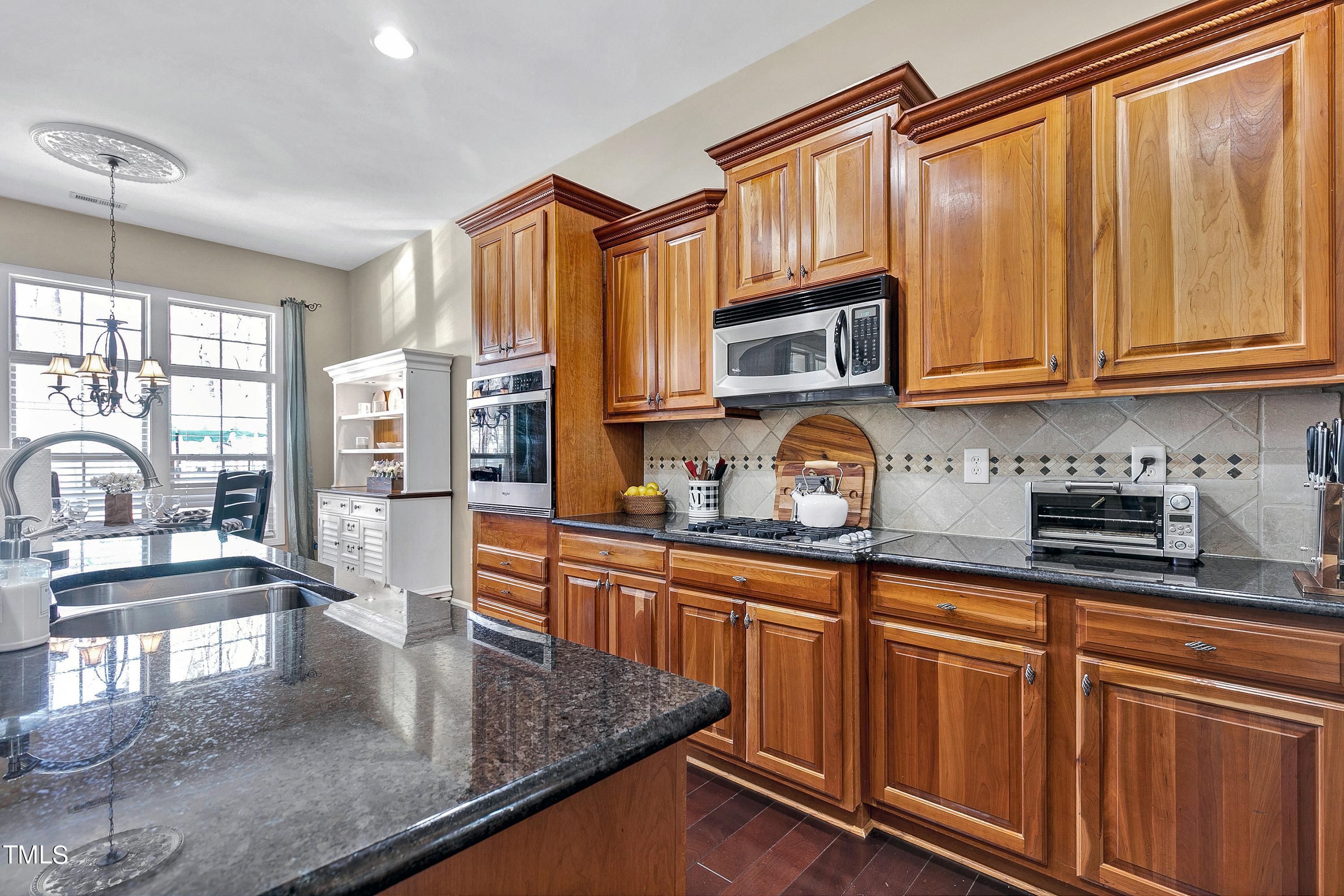 6115 Leesburg Lane Raleigh, NC 27617 - Photo 15 of 46 a kitchen with stainless steel appliances granite countertop a stove a sink dishwasher and cabinets with wooden floor
