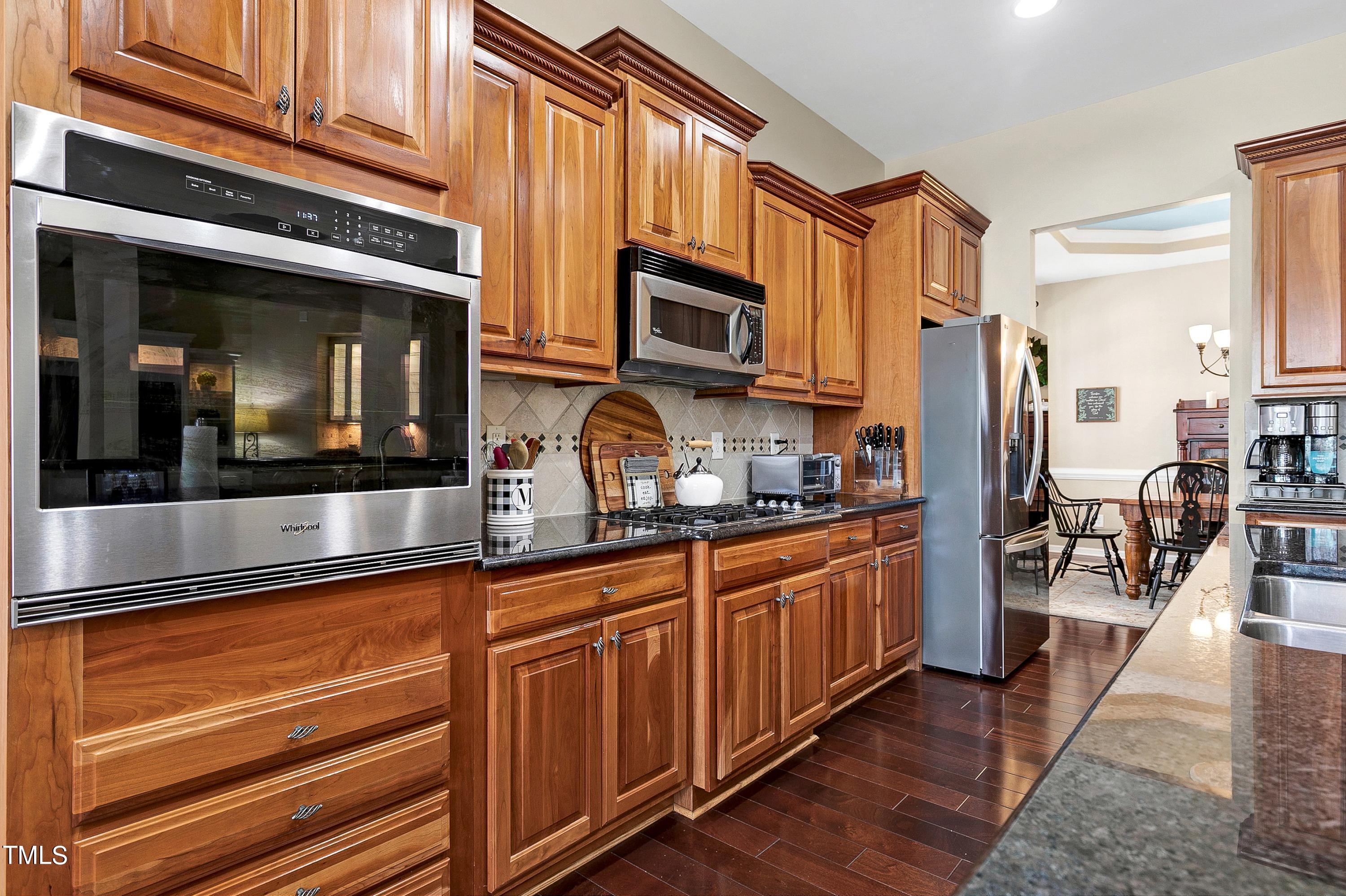 6115 Leesburg Lane Raleigh, NC 27617 - Photo 19 of 46 a kitchen with stainless steel appliances granite countertop a refrigerator a stove and a sink with wooden floor