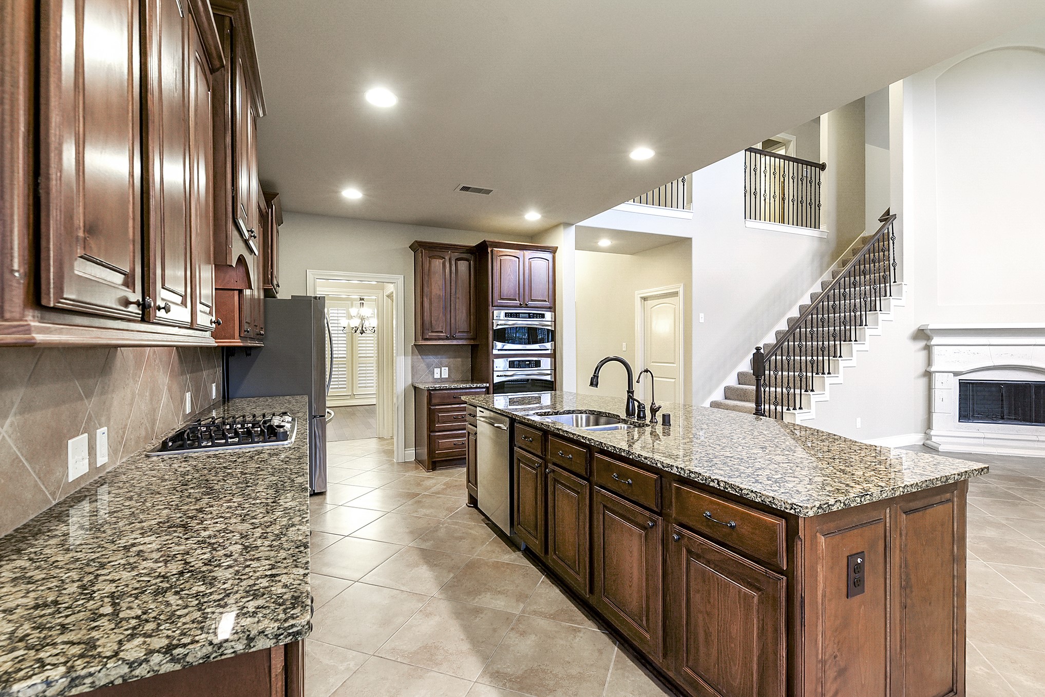 29023 Powder Ridge Drive Katy, TX 77494 - Photo 18 of 50 The kitchen offers an abundance of cabinets and drawers with hardware, providing ample storage and functionality. Granite countertops complement the rich wood cabinetry, creating a warm and inviting design. A spacious countertop ties in the natural wood tones, while the vented range hood, built-in microwave, and built-in oven add convenience and functionality to this well-appointed kitchen.
