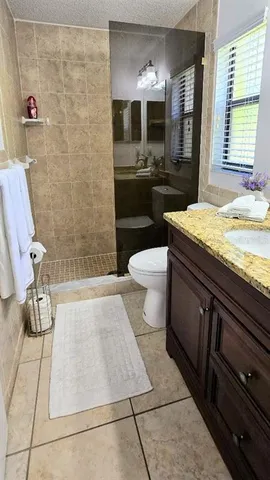 a bathroom with a granite countertop sink a toilet a mirror and bathtub