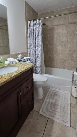 a bathroom with a granite countertop sink a toilet and bathtub