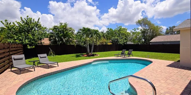 a view of pool with lawn chairs and a big yard
