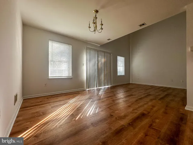 a view of an empty room with window and wooden floor
