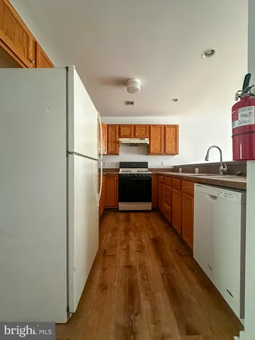 a kitchen with stainless steel appliances granite countertop a refrigerator a sink a stove and white cabinets