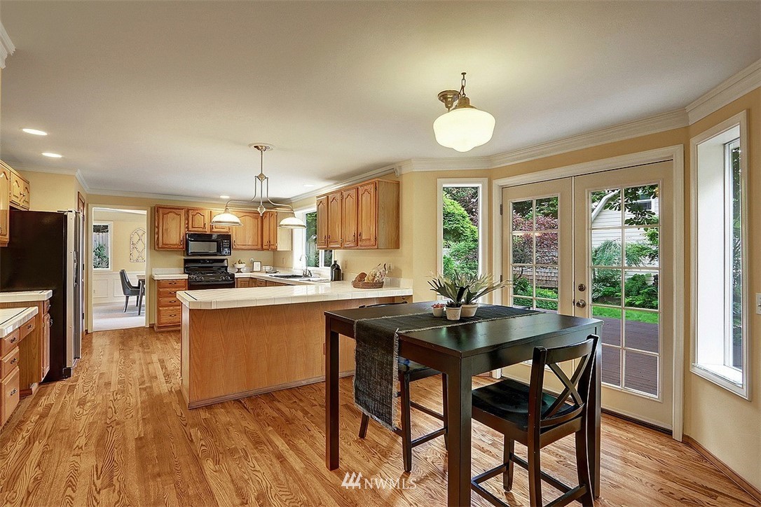 220 174th Street Southwest Bothell, WA 98012 - Photo 3 of 35 a kitchen with stainless steel appliances granite countertop a stove a refrigerator a sink a dining table and chairs with wooden floor