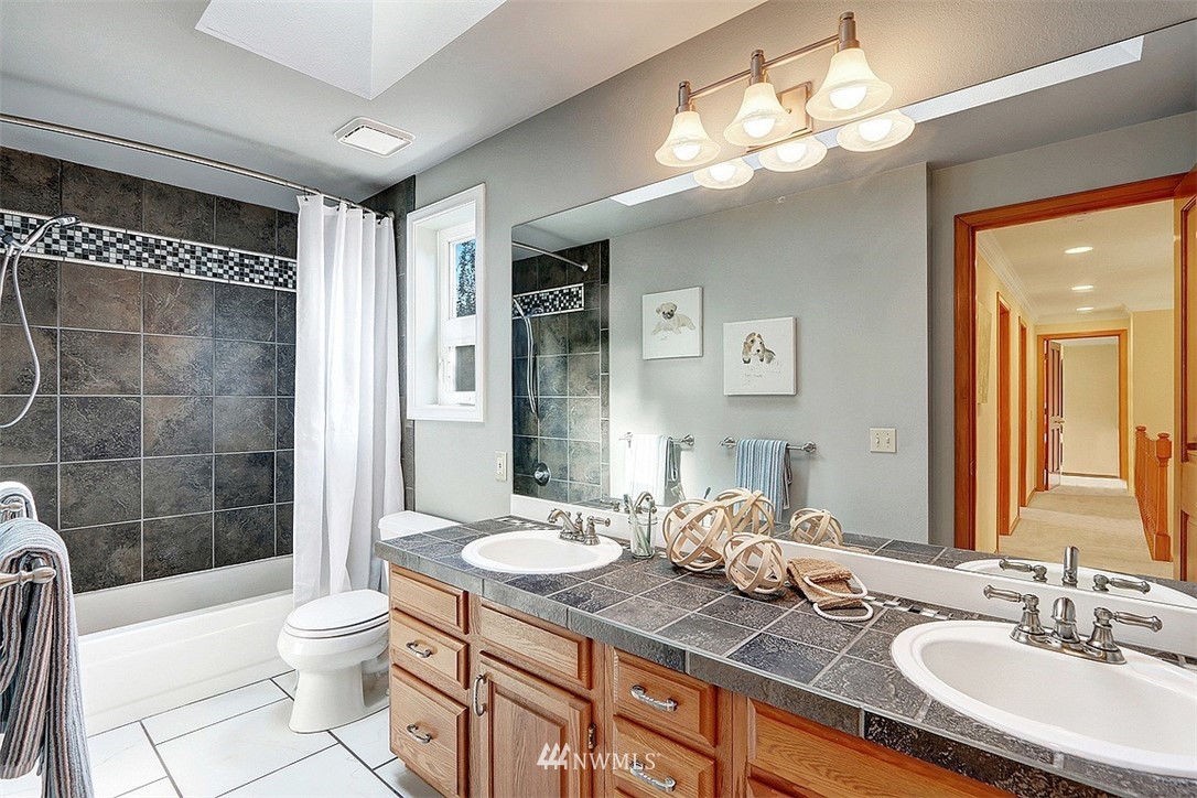 220 174th Street Southwest Bothell, WA 98012 - Photo 22 of 35 a bathroom with a granite countertop sink toilet a mirror a vanity and shower
