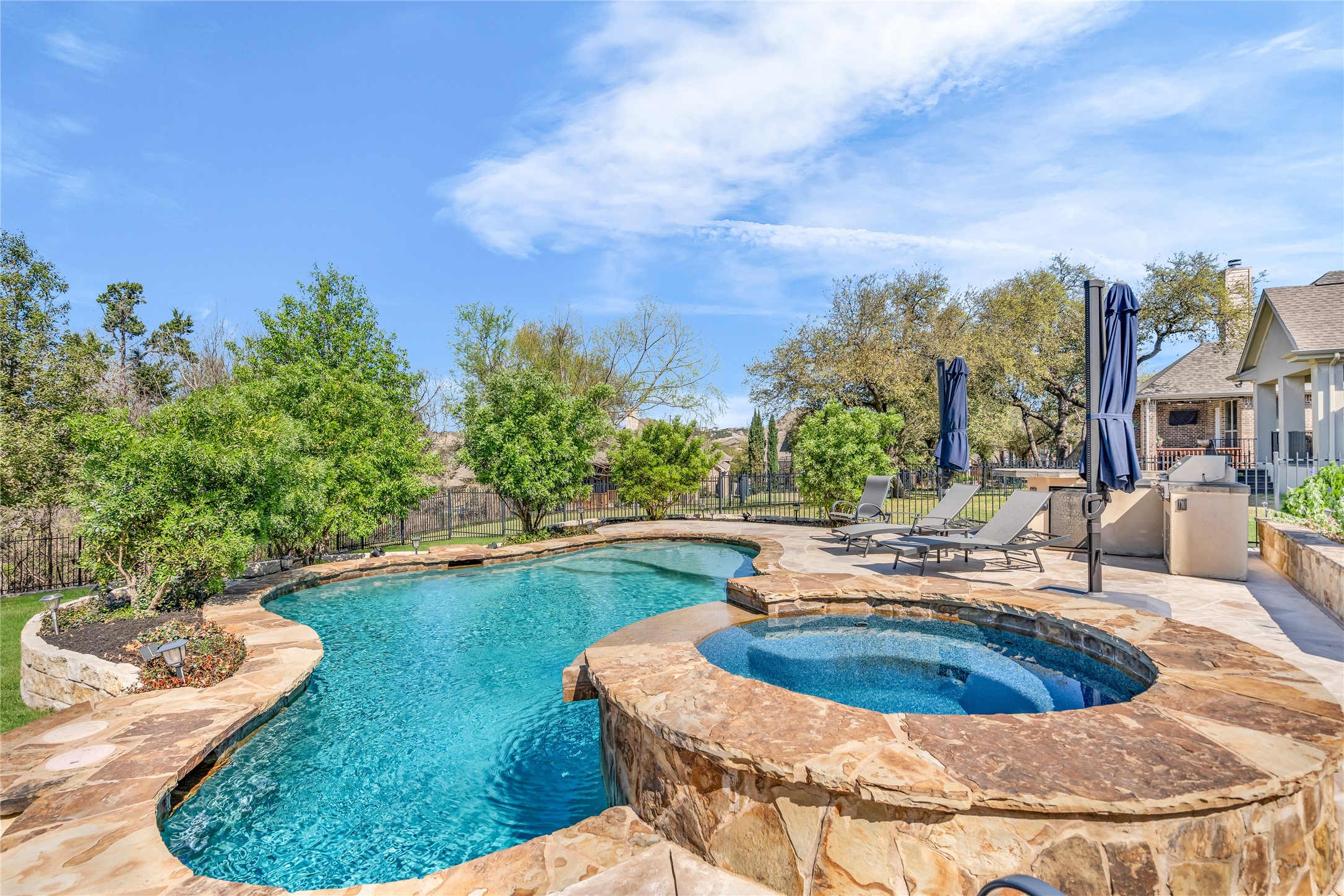 3925 Goodnight Trail Leander, TX 78641 - Photo 2 of 25 Combined pool / hot tub with a fenced backyard, a patio area, and an outdoor kitchen