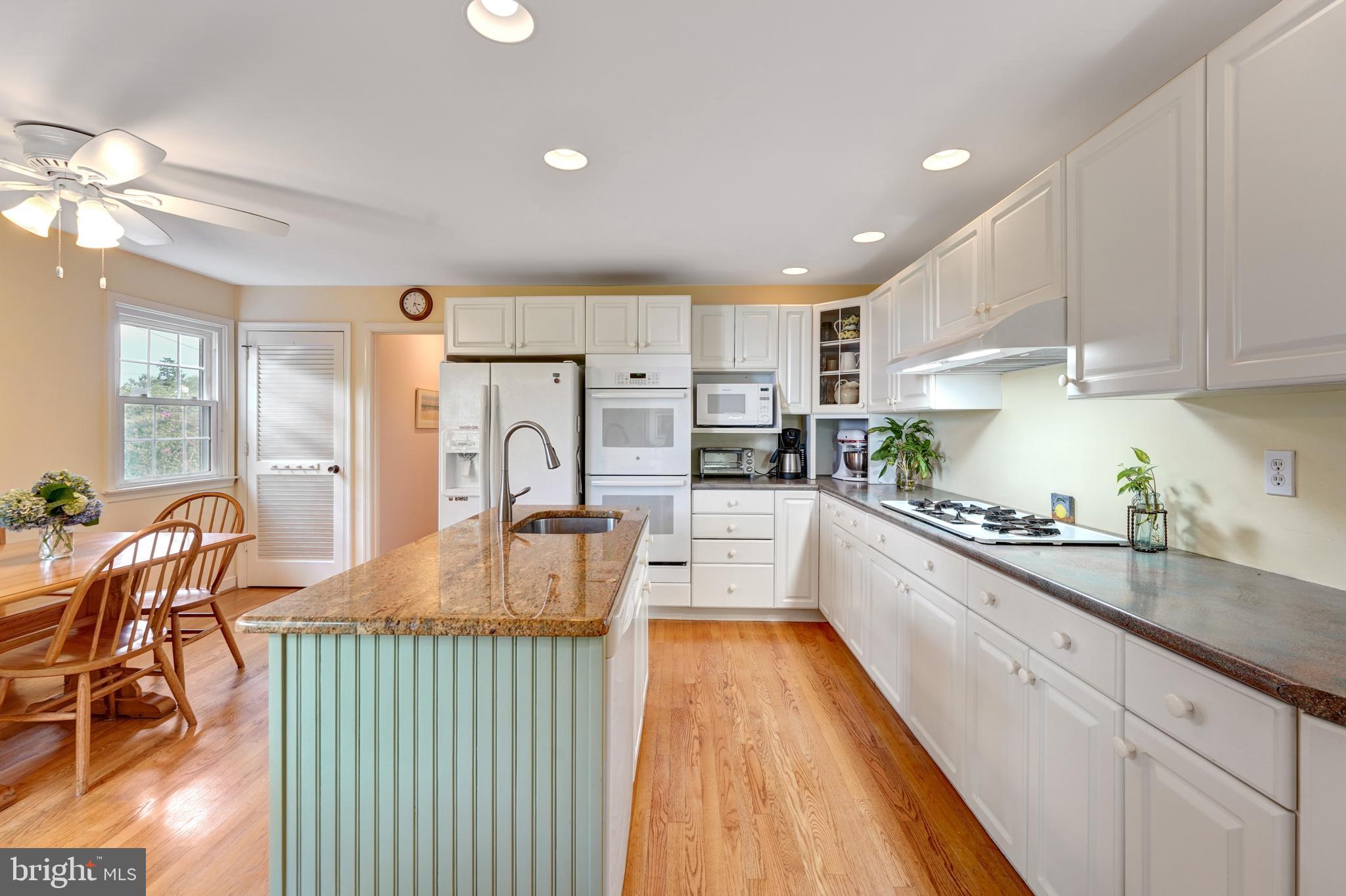 60 East Clearfield Road Havertown, PA 19083 - Photo 15 of 57 a large kitchen with stainless steel appliances granite countertop a stove a sink dishwasher a dining table and chairs with wooden floor