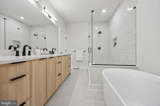 a bathroom with a double vanity sink a mirror a bathtub and shower