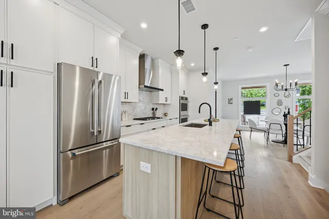 a kitchen with stainless steel appliances granite countertop a refrigerator a sink a stove and white cabinets with wooden floor