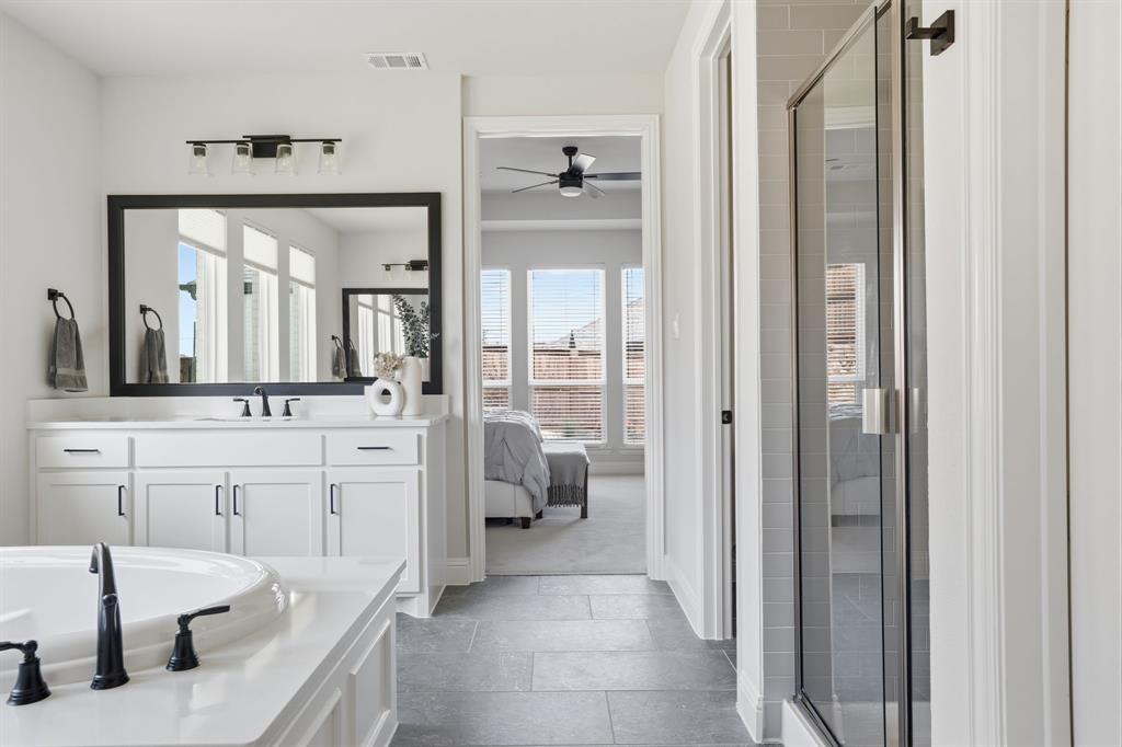 4202 Crown Run Road Midlothian, TX 76065 - Photo 16 of 34 Bathroom featuring a deep soaking tub with matte black fixtures, a dual-sink vanity with white cabinetry, a frameless shower with tile surround, and gray tile flooring