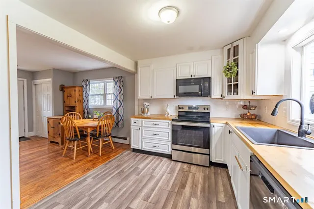 a kitchen with a stove top oven a sink dishwasher a dining table and chairs with wooden floor