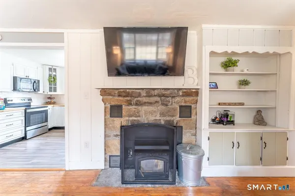 a living room with stainless steel appliances furniture a fireplace and a kitchen view