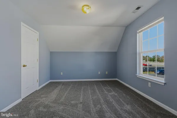 a view of an empty room with closet and a window