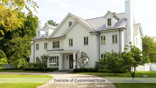 a view of a white house next to a yard with big trees