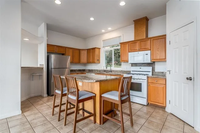 a kitchen with stainless steel appliances kitchen island granite countertop a refrigerator and a stove top oven