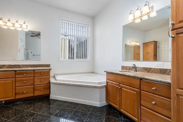 a bathroom with a granite countertop double vanity sink mirror and bathtub