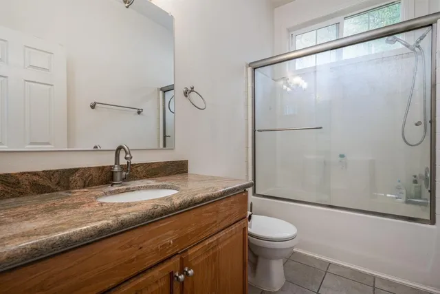 a bathroom with a granite countertop sink toilet and shower