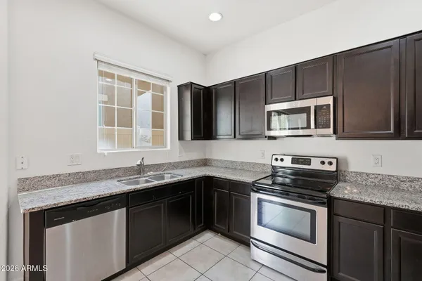 a kitchen with granite countertop a sink stove and microwave