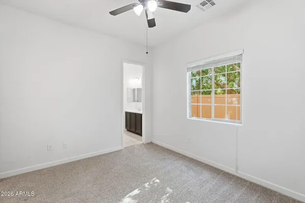 an empty room with windows and chandelier fan