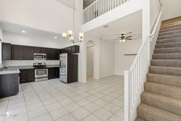 a kitchen with stainless steel appliances kitchen island granite countertop a refrigerator a stove a sink dishwasher and white cabinets with wooden floor